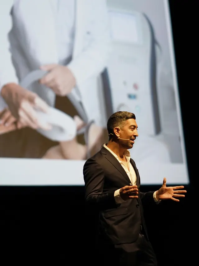 Dr Podlipnik giving a talk at a medical conference, with an IPL image projected behind him
