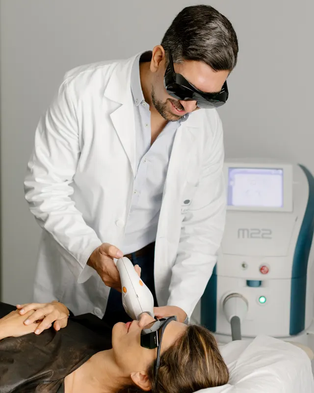 Dr Podlipnik applying IPL to a patient's face, both wearing protective eyewear
